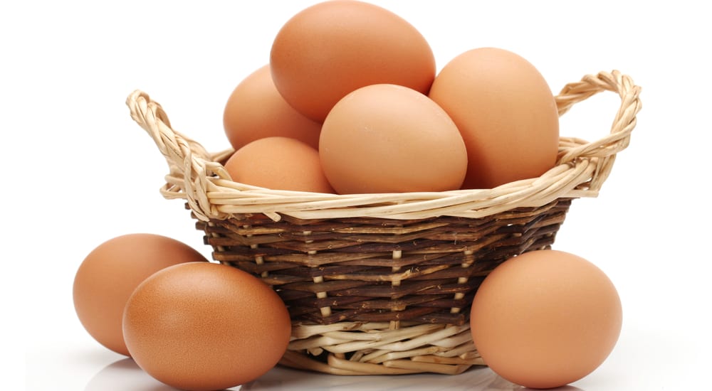 Pile of eggs in a wicker basket with a white background