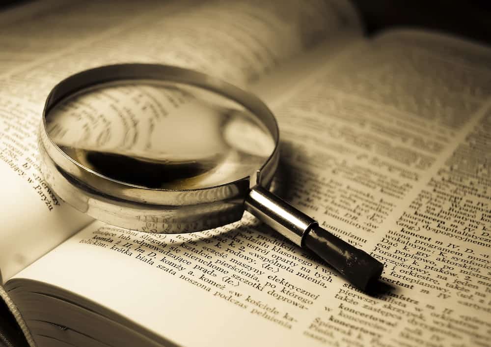 Magnifying glass sitting on top of a dictionary about common SEO terms