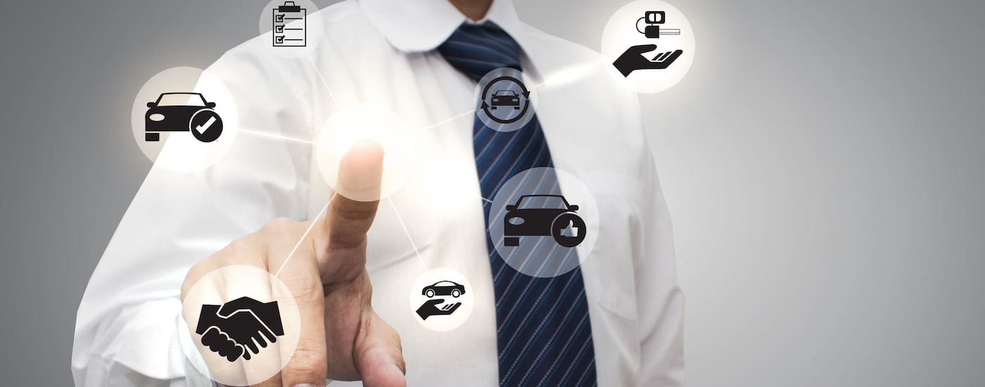 Businessman pointing at digital figures that represent different aspects of automotive marketing